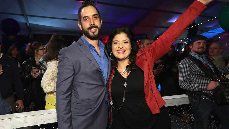 Alex Guarnaschelli and Michael Castellon at a party, with Guarnaschelli's arm raised in the air