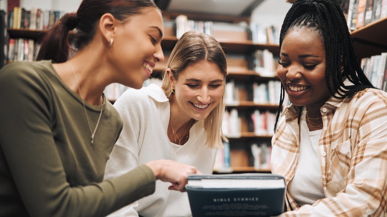 Group of three women smiling while talking about book