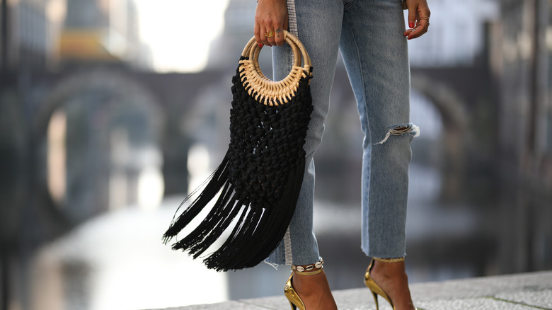 Woman holding black fringe bag