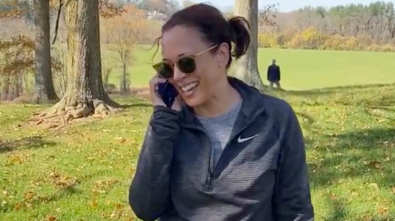 Kamala Harris smiling and talking on phone in a Nike pullover while outside