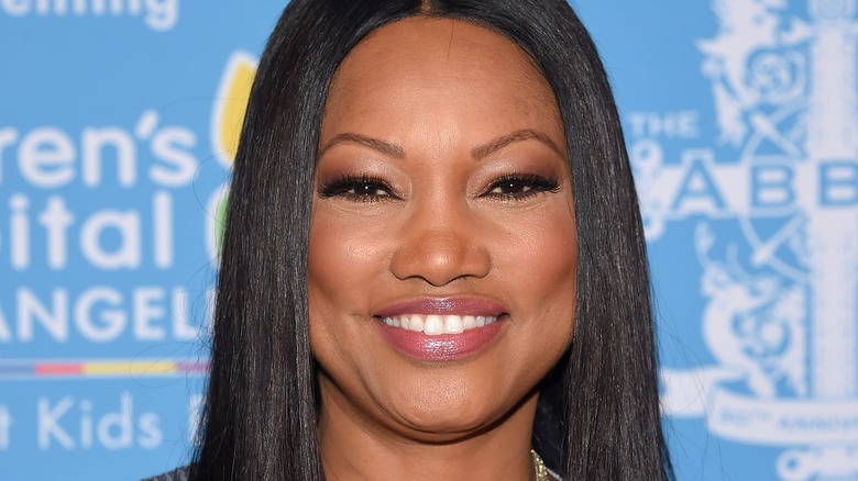 Garcelle Beauvais smiling with blue backdrop