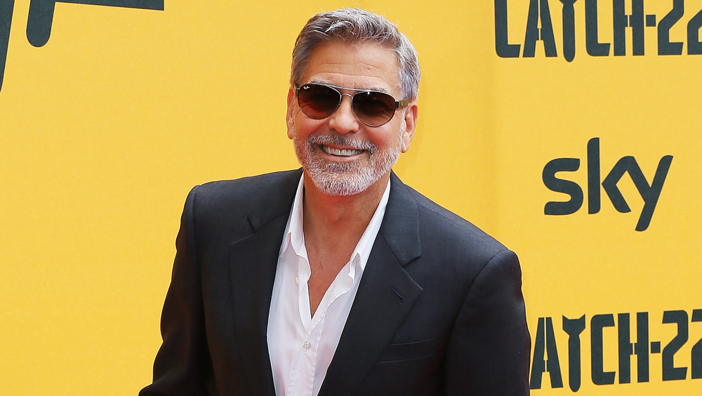 George Clooney smiling on the red carpet in sunglasses