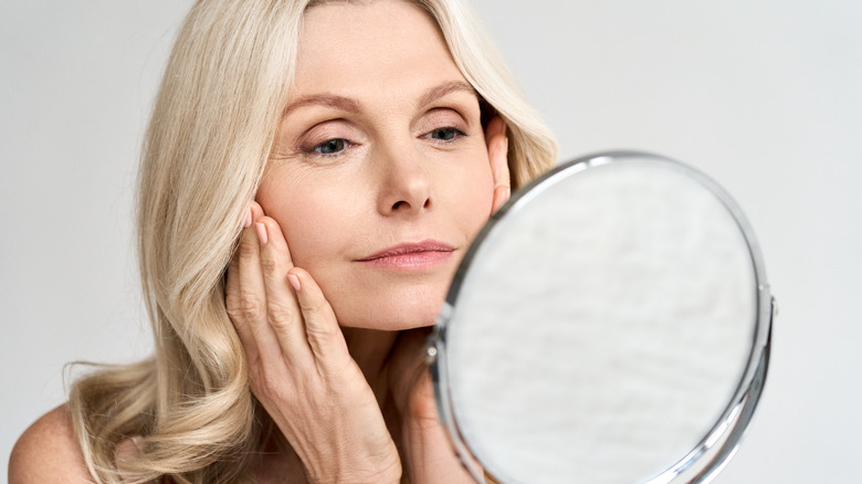 Woman putting on lotion in mirror