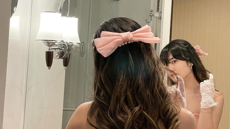 woman with hair bow looking in mirror