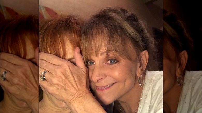 Susie McEntire-Eaton covering her sister Reba's face while smiling