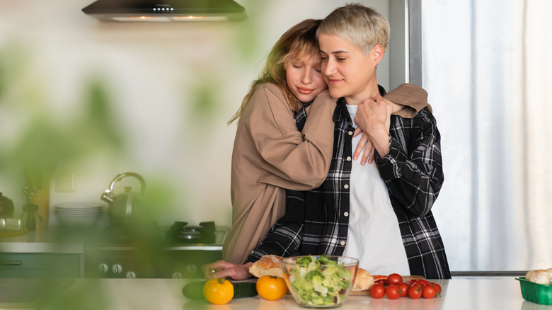 LGBTQIA+ couple embracing, making dinner 