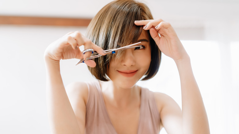 Smiling woman trimming her bangs