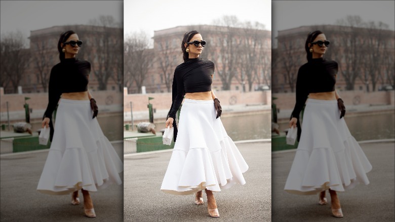 woman black top white skirt sunglasses big earrings