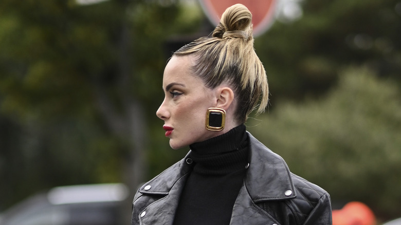 woman bun black biker jacket big gold earrings