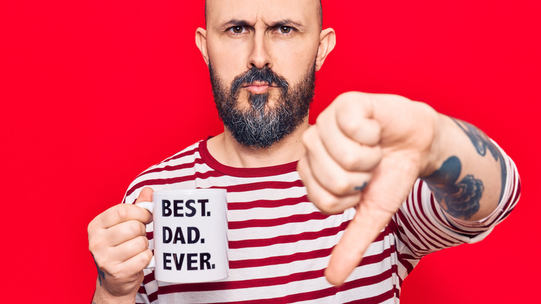 Man giving thumbs down holding "best dad ever" mug