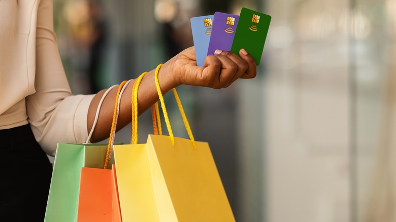 person with colorful bags holding up "gift cards"