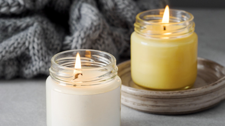 yellow and white candles, both burning. gray throw blanket in background