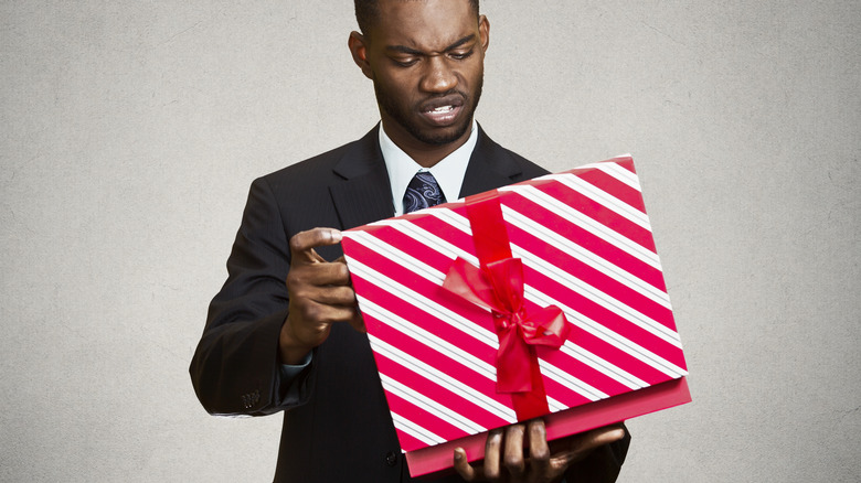 man in suit disgruntled opening present