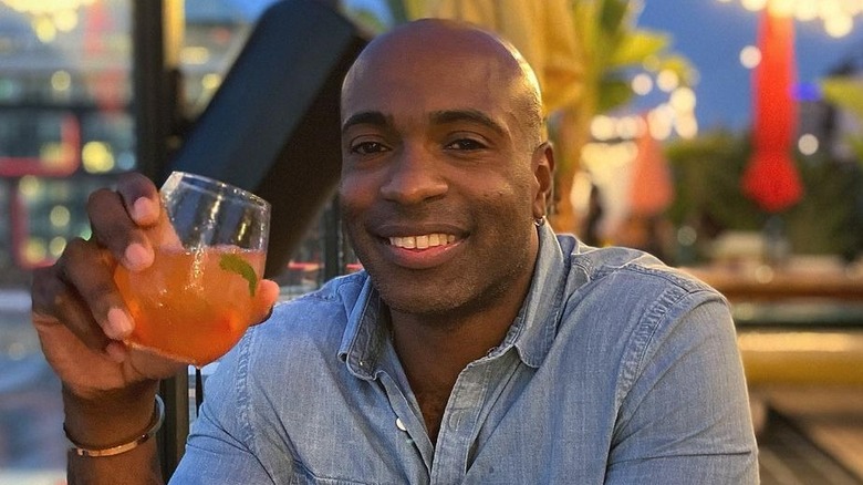 Gil Cuero holding a drink and smiling