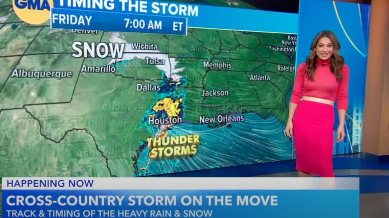 Meteorologist Ginger Zee in a pink dress in front of a weather map