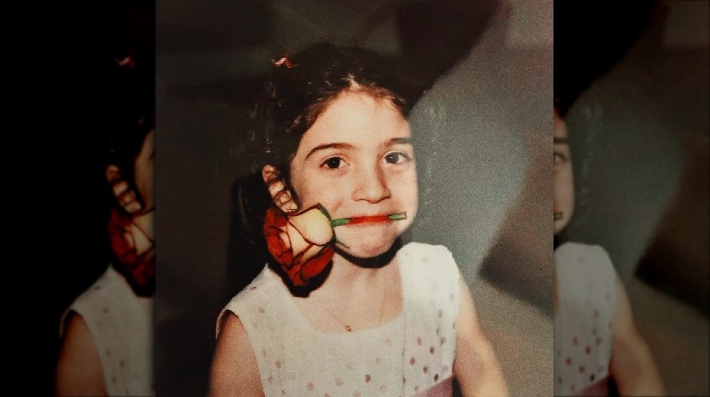 Gloria Estefan's daughter, Emily Estefan, as a girl with a rose in her mouth