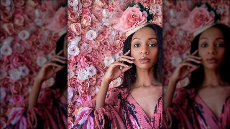 model touching cheek, wearing rose fascinator