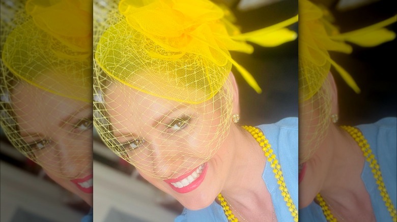 Smiling woman in yellow birdcage hat