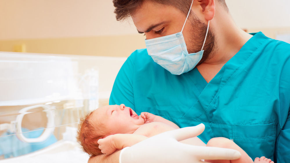 Masked doctor holding baby