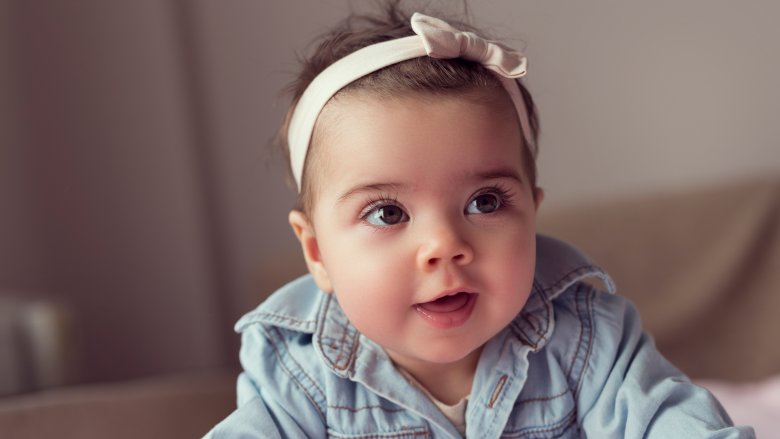 smiling baby in jean jacket and pink headband bow