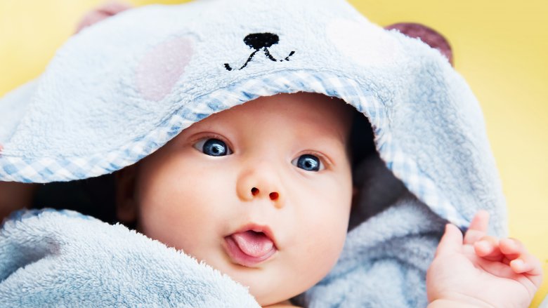 baby in blue towel with tongue out