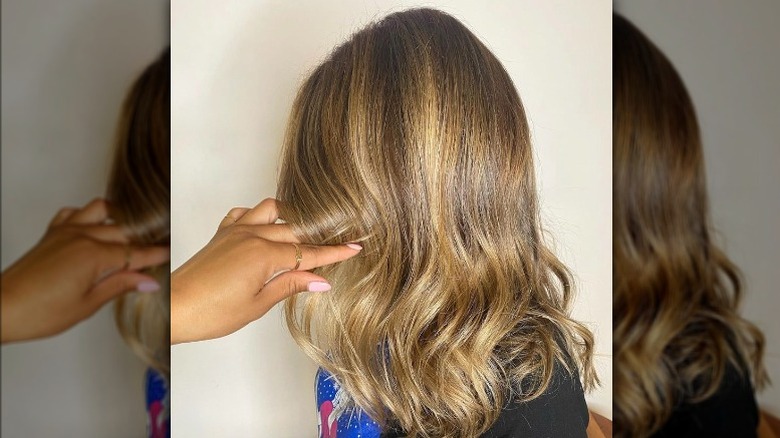 Hand holding hair with honey highlights