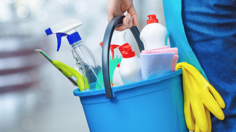 Hand holding bucket of cleaning products