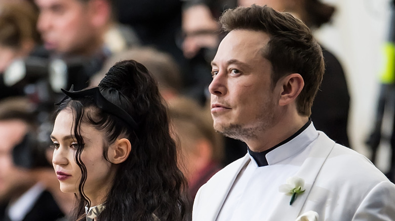 Grimes looking annoyed and Elon Musk looking suspicious