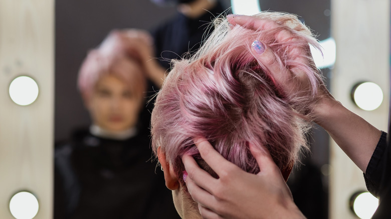 Hairstylist designing client's short pink hair