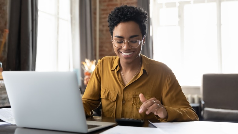 woman works on calculator and laptop