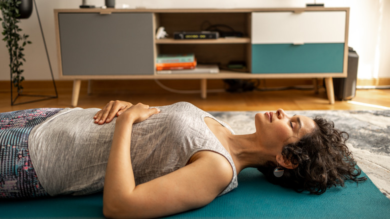 Woman lies on yoga mat and does breathing exercises