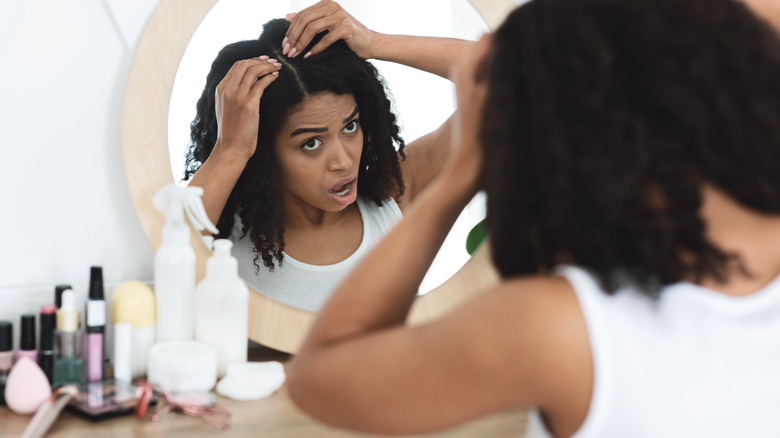 Woman inspecting her scalp in mirror