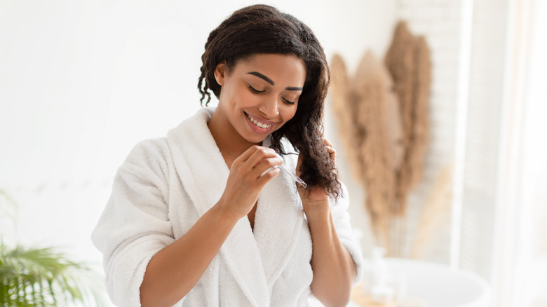 woman putting serum on her hair, applying serum to hair