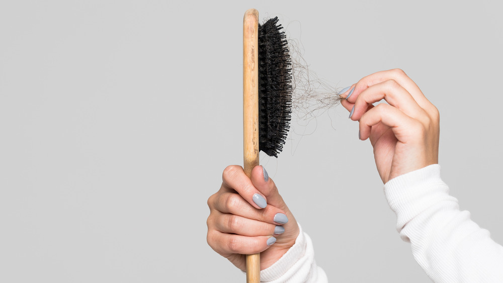 Woman pulling hair from brush