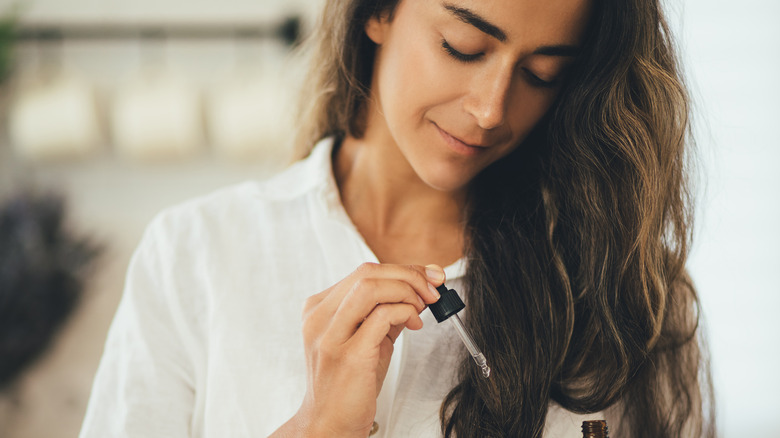 Woman oiling hair with dropper