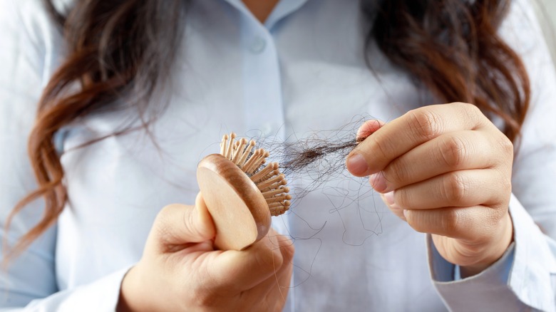 woman pulling hair out of hairbrush