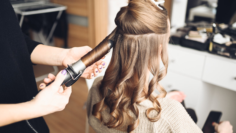 Woman getting hair curled at hair salon