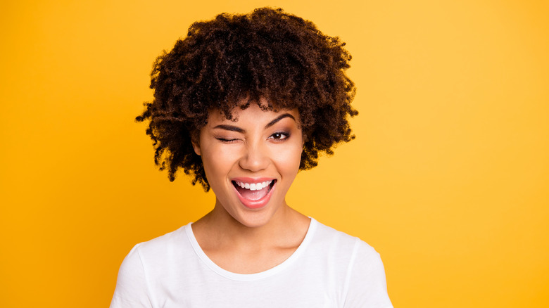 Woman with natural hair smiling and winking