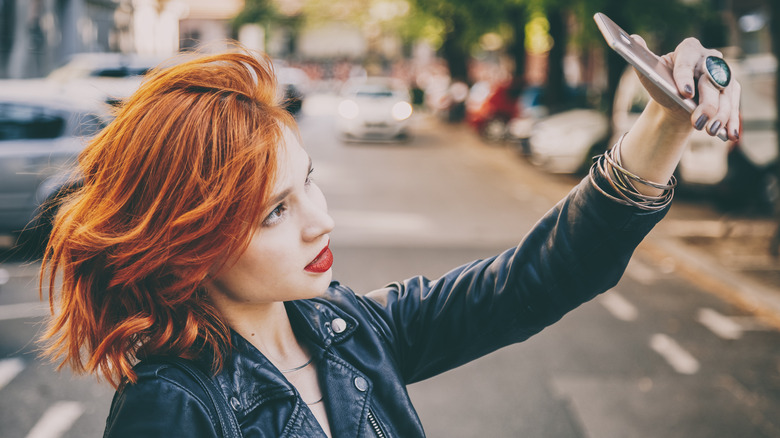A woman with copper hair taking a selfie