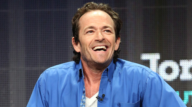 Luke Perry smiling in blue shirt