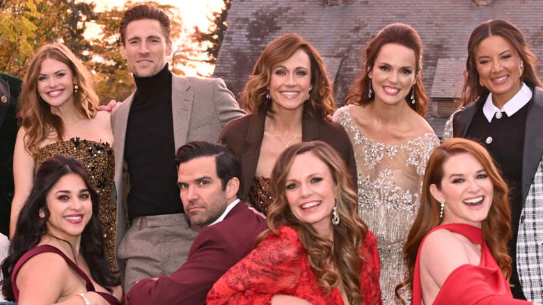 Holland Roden, Andrew Walker, Nikki DeLoach, Erin Cahill, Heather Hemmens, Noemí González, Benjamin Ayres, Rachel Boston, and Sarah Drew sit together on a bench