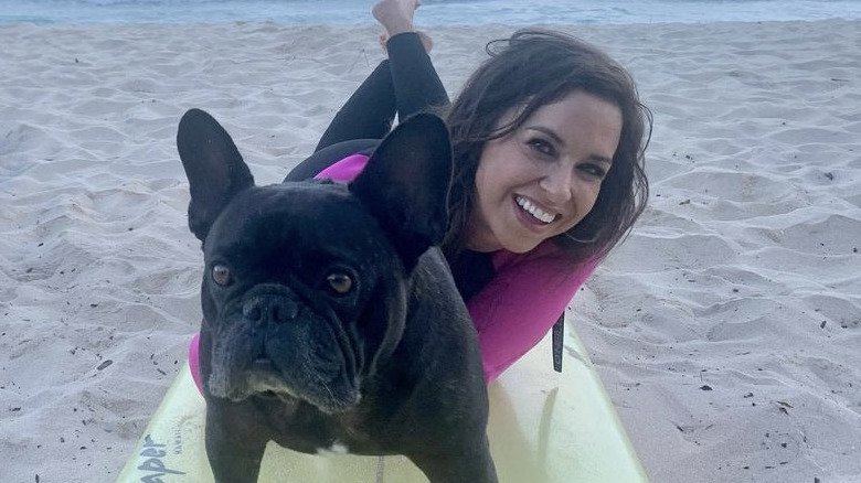 Lacey Chabert lying on surfboard with dog