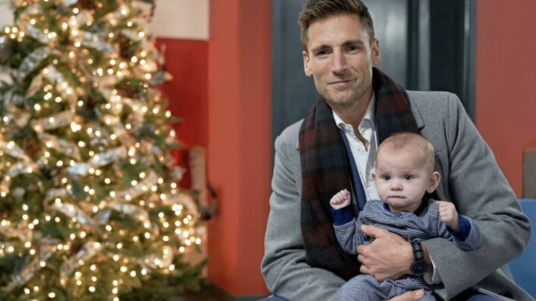 Andrew Walker and baby next to Christmas tree posing for Three Wise Men and a Baby