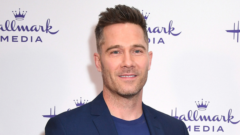 Luke Macfarlane smiles at an event for Hallmark