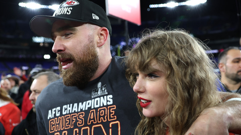 Travis Kelce and Taylor Swift stand together on football field