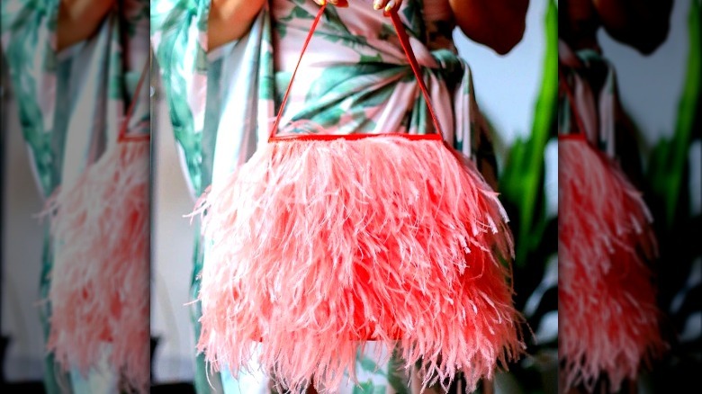 Model holding a pink feather handbag