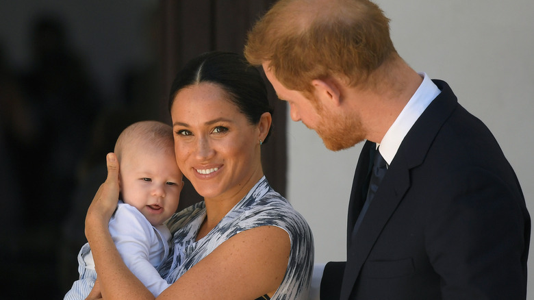 Prince Harry looking at Meghan Markle holding Prince Archie