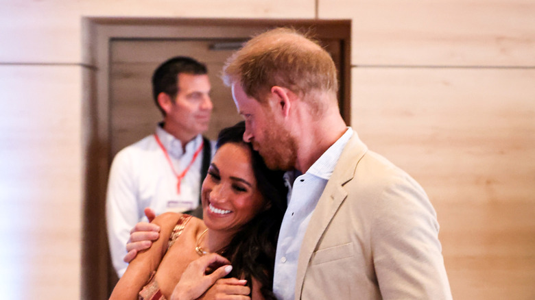 Prince Harry kisses the top of Meghan Markle's head