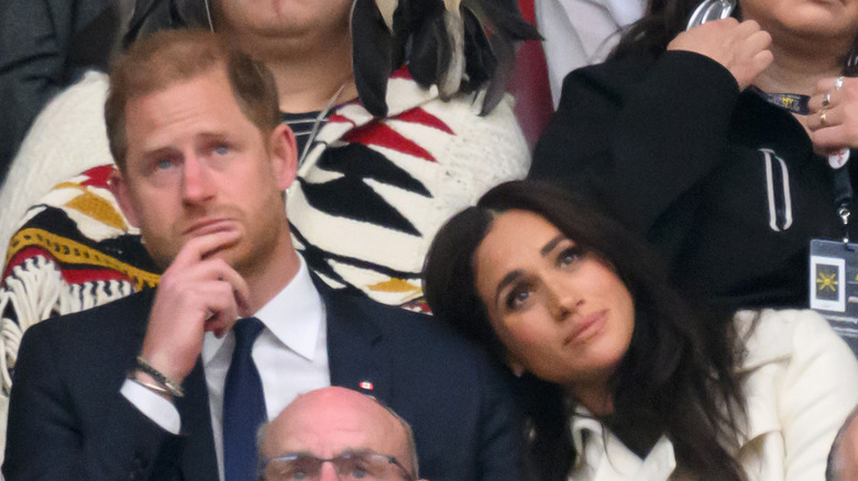 Prince Harry thinking with Meghan Markle leaning on his shoulder