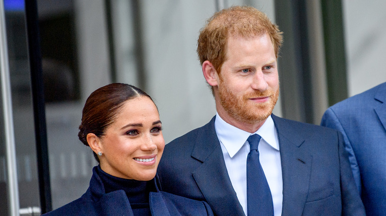 Prince Harry and Meghan Markle smiling at an event.